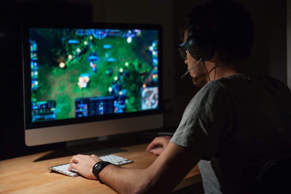 גבר יושב מול מסך מחשב ונהנה משני עולמות של משחק ופיתוח